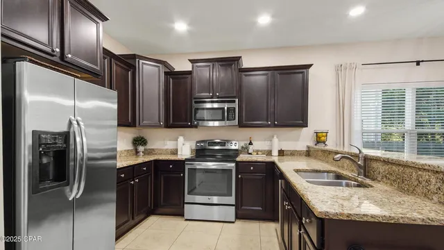 a kitchen with stainless steel appliances granite countertop a stove a sink dishwasher a refrigerator and a oven with wooden floor