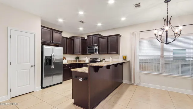 a view of kitchen with stainless steel appliances granite countertop a refrigerator and a stove top oven