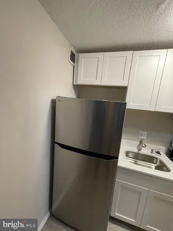 a close view of a refrigerator in kitchen and an empty room