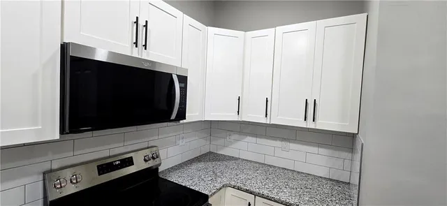 a kitchen with granite countertop white cabinets and black appliances
