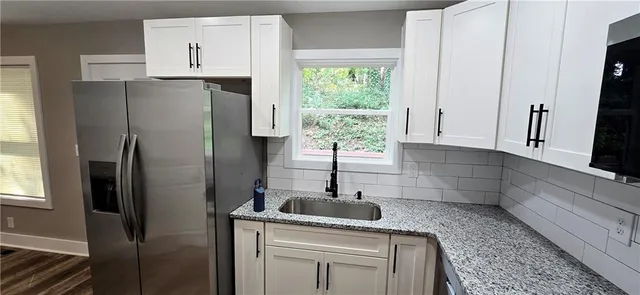 a kitchen with stainless steel appliances granite countertop a refrigerator sink and white cabinets