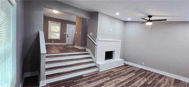 a view of a livingroom with wooden floor a ceiling fan and staircase