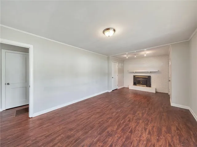 an empty room with wooden floor cabinet and windows