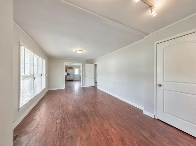 a view of an empty room with a window and wooden floor