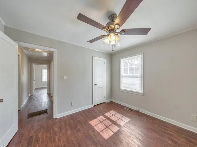 an empty room with wooden floor closet and fan