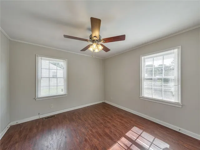 a view of an empty room with window and wooden floor