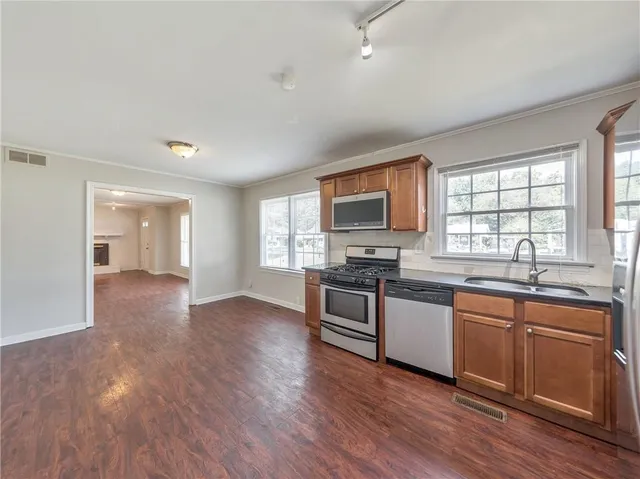 a kitchen with stainless steel appliances granite countertop a stove a sink and a microwave