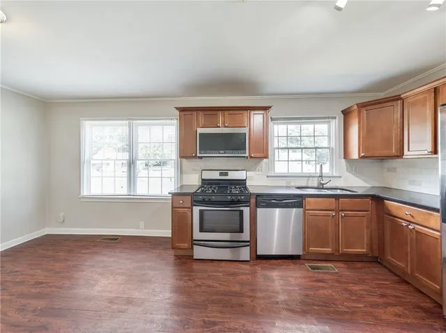 a large kitchen with cabinets wooden floor and stainless steel appliances