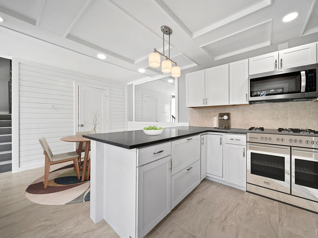 5992 Southeast Riverboat Drive, Unit 537 Stuart, FL 34997 - Photo 4 of 14 a kitchen with granite countertop a sink a stove and microwave