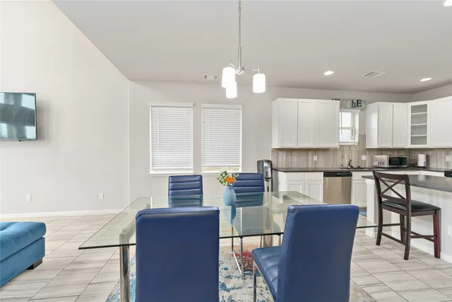 a kitchen with stainless steel appliances granite countertop a stove top oven a sink dishwasher a dining table and chairs with wooden floor