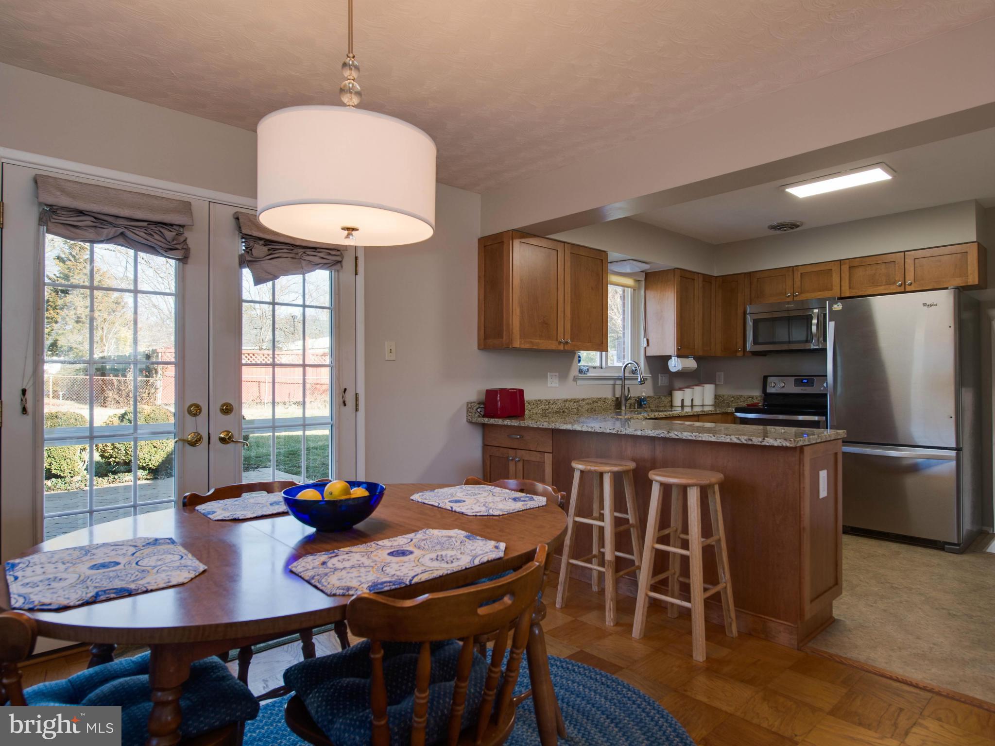 5223 Cather Road Springfield, VA 22151 - Photo 7 of 22 a kitchen with stainless steel appliances granite countertop a stove a refrigerator a kitchen island a table and chairs