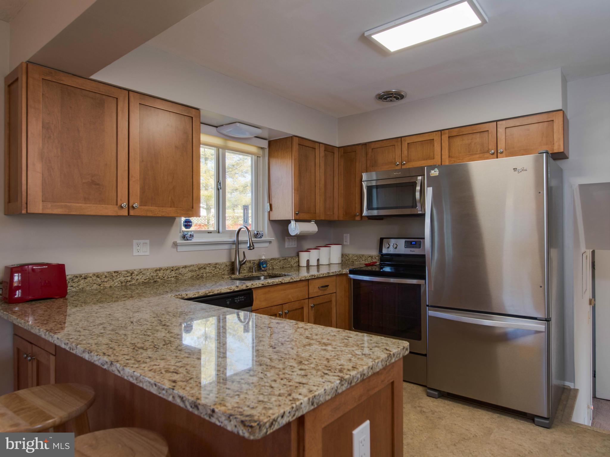 5223 Cather Road Springfield, VA 22151 - Photo 8 of 22 a kitchen with granite countertop a refrigerator stove and sink