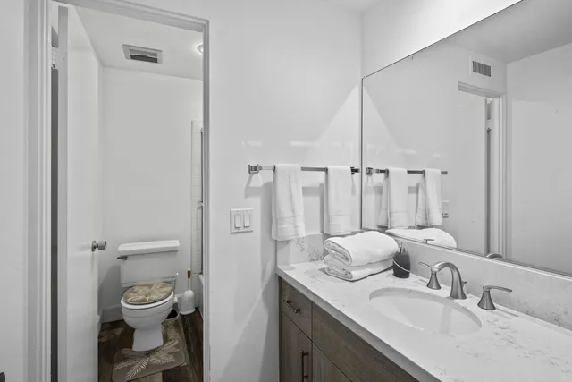 a bathroom with a granite countertop sink toilet a mirror and shower