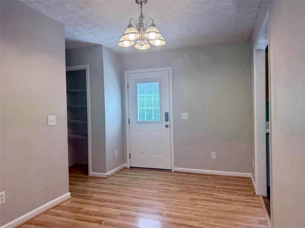 6258 Southern Magnolia Lane Lula, GA 30554 - Photo 5 of 17 an empty room with wooden floor chandelier and closet area