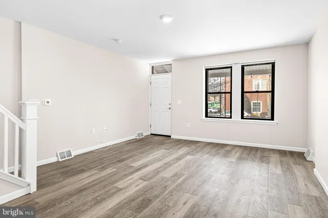 an empty room with wooden floor and windows