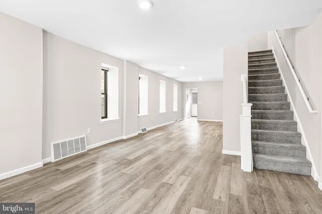 a view of an empty room with wooden floor and stairs