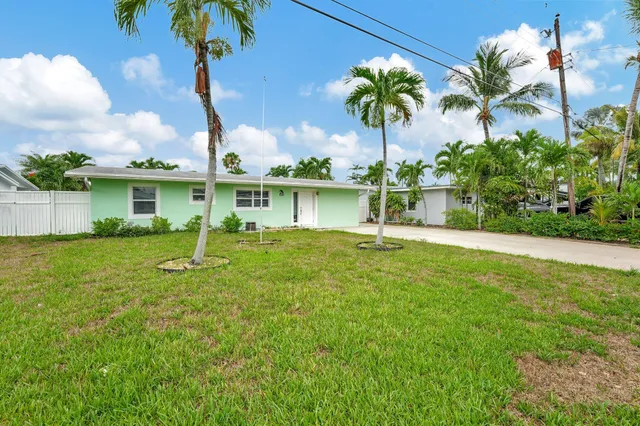 front view of house with a yard and palm trees