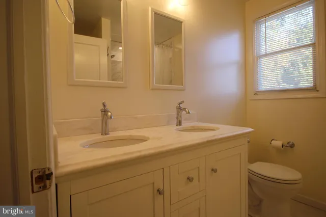 a bathroom with a granite countertop sink toilet and mirror