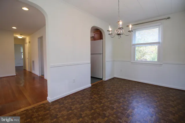 an empty room with chandelier fan and windows