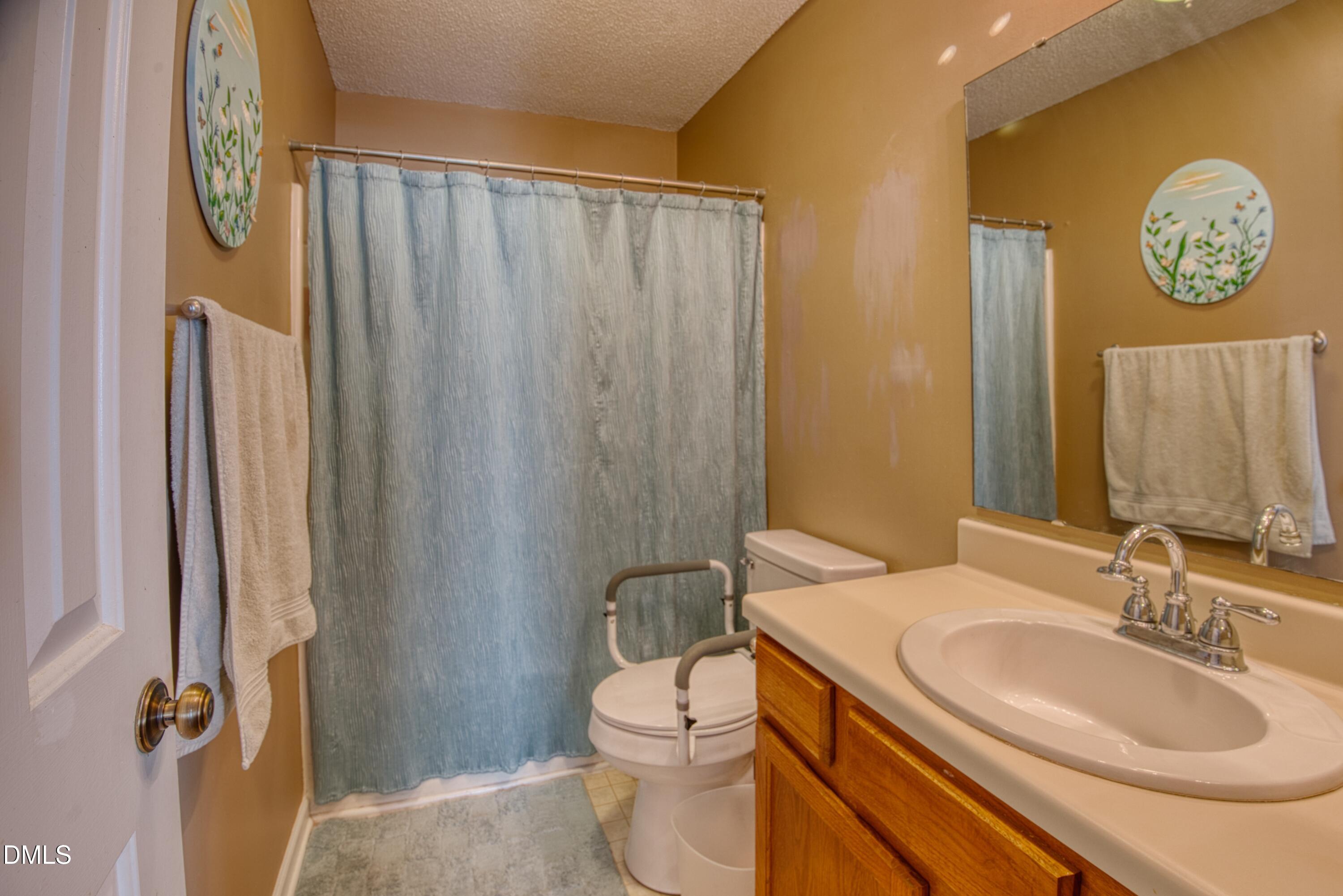 4641 Timbermill Court, Unit 302 Raleigh, NC 27612 - Photo 14 of 27 a bathroom with a toilet a sink and a mirror