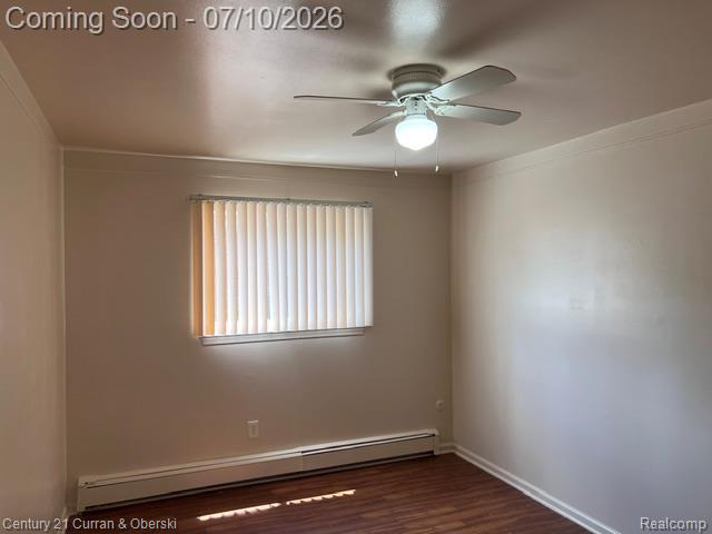 14682 Middle Gibraltar Road, Unit 24 Rockwood, MI 48173 - Photo 13 of 21 Room featuring wood-finish flooring, a window with vertical blinds, baseboard heating, a ceiling fan with integrated lighting, and crown molding