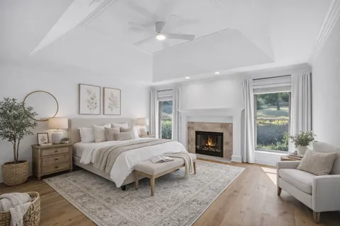 an empty room with wooden floor fireplace and windows