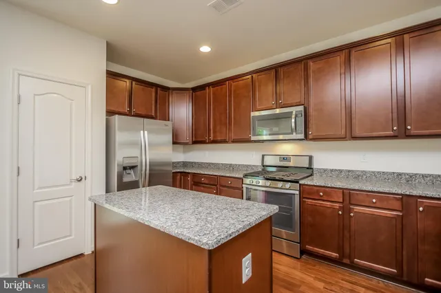 a kitchen with stainless steel appliances granite countertop wooden cabinets a stove a sink and a refrigerator