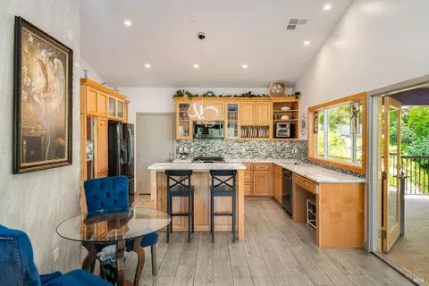 a open kitchen with stainless steel appliances granite countertop a stove a refrigerator a sink dishwasher a dining table and chairs with wooden floor