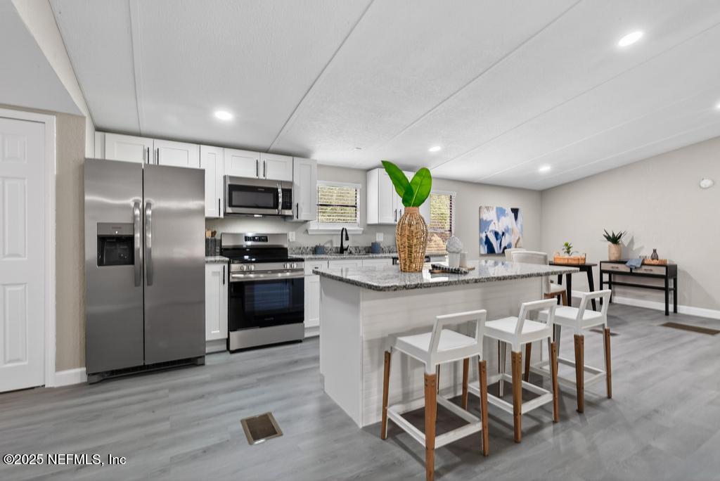 95422 Plum Loop Fernandina Beach, FL 32034 - Photo 23 of 76 a kitchen with stainless steel appliances a refrigerator a stove a sink a dining table and chairs with wooden floor