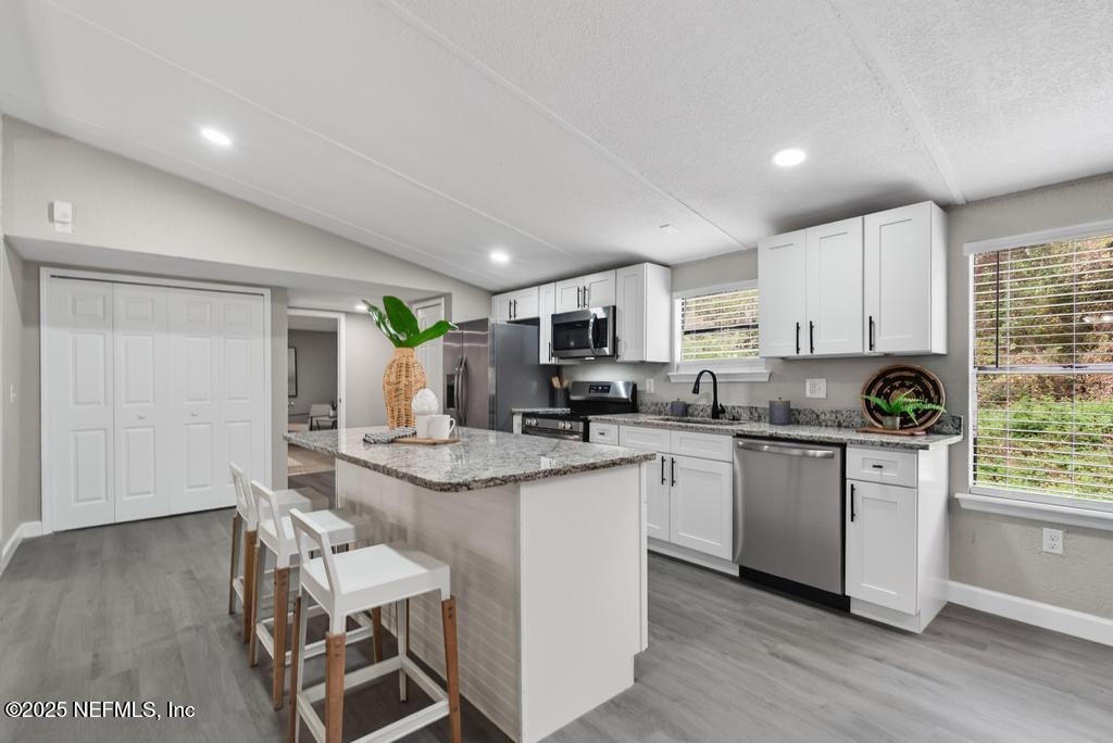 95422 Plum Loop Fernandina Beach, FL 32034 - Photo 26 of 76 a kitchen with kitchen island granite countertop wooden floors and white cabinets