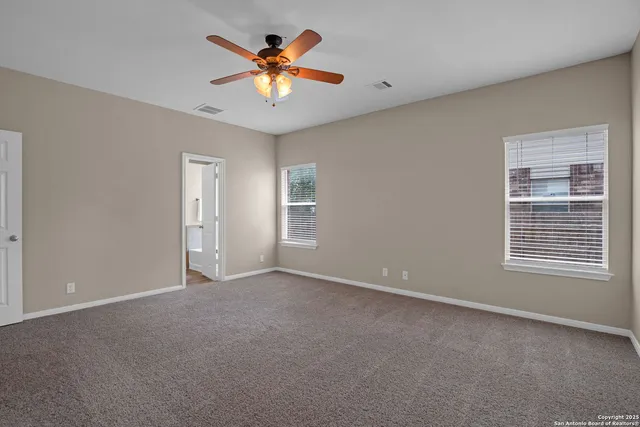 a view of an empty room with a ceiling fan and window