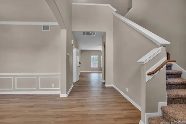 a view of a hallway with wooden floor and staircase