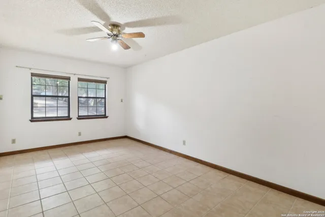 an empty room with windows and ceiling fan