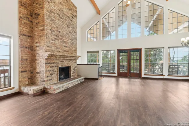 a view of an empty room with wooden floor and a fireplace
