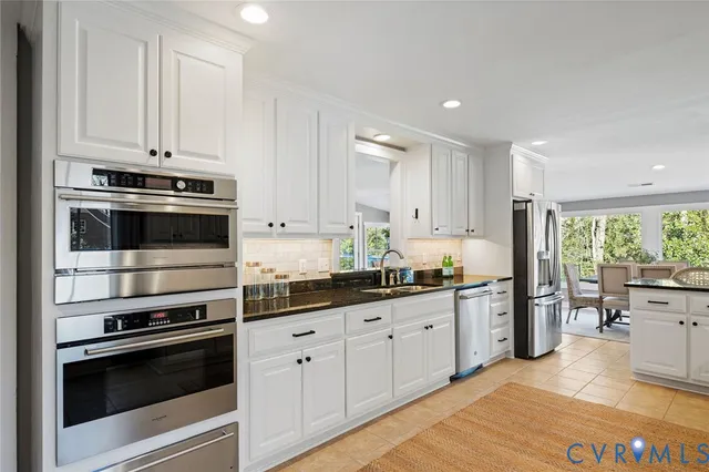 a kitchen with stainless steel appliances granite countertop a stove and white cabinets