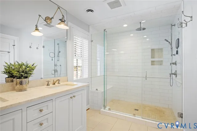 a bathroom with a double vanity sink mirror and shower