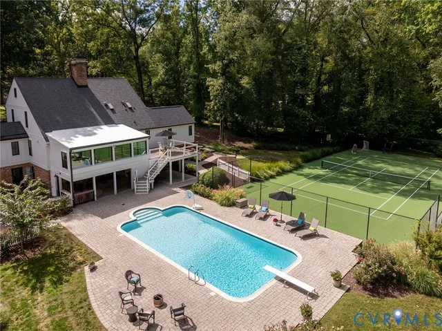 an aerial view of a house with swimming pool and large trees