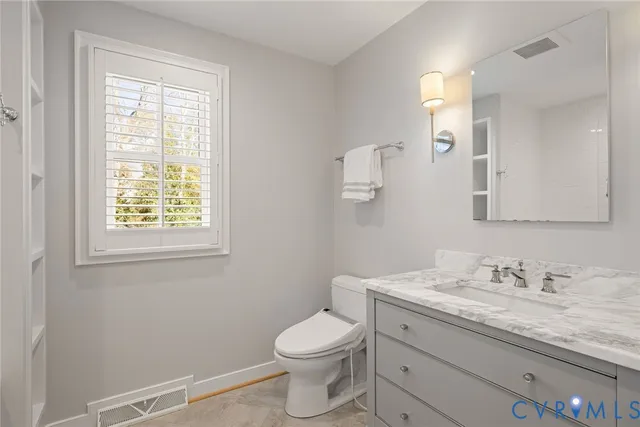 a bathroom with a granite countertop toilet a sink and mirror
