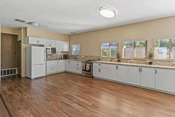 a large kitchen with stainless steel appliances granite countertop a stove a sink dishwasher and a refrigerator