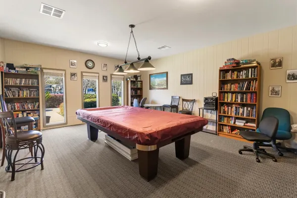 a spacious bedroom with a bed a table and a bookshelf