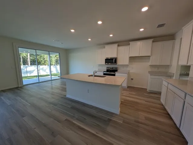 a large kitchen with stainless steel appliances granite countertop a large counter top a stove and a wooden floors