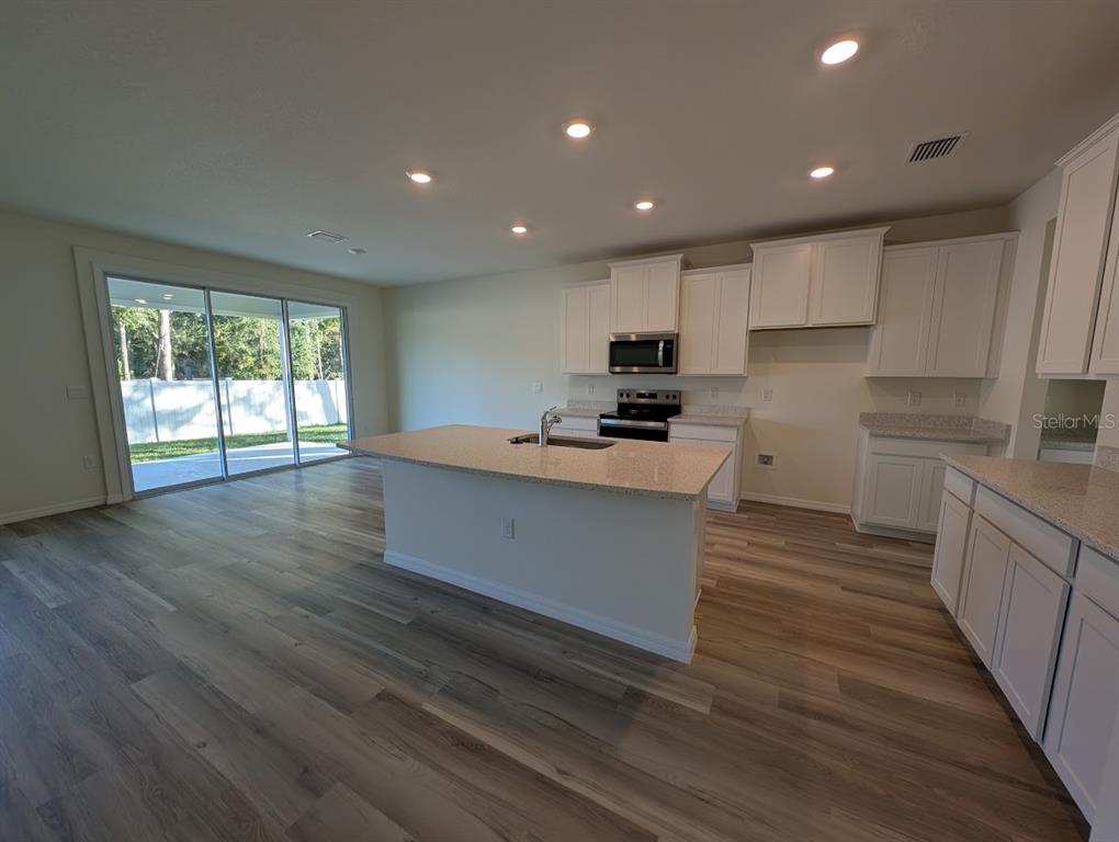 5173 Southwest 52nd Drive Gainesville, FL 32608 - Photo 4 of 14 a large kitchen with stainless steel appliances granite countertop a large counter top a stove and a wooden floors