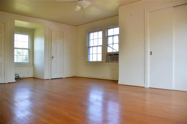 an empty room with wooden floor and windows