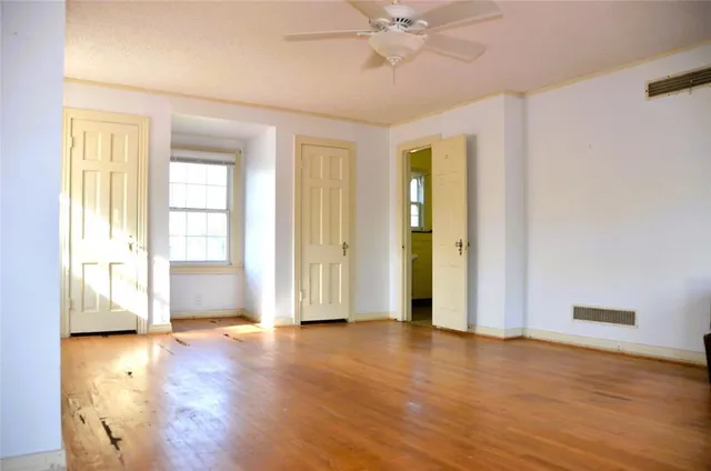 a view of an empty room with window and wooden floor