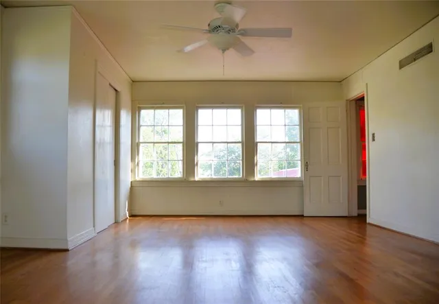 an empty room with wooden floor and windows