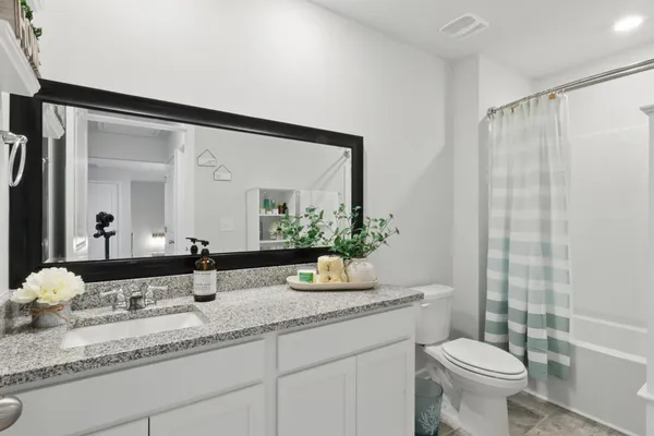 a bathroom with a granite countertop sink a toilet and a mirror
