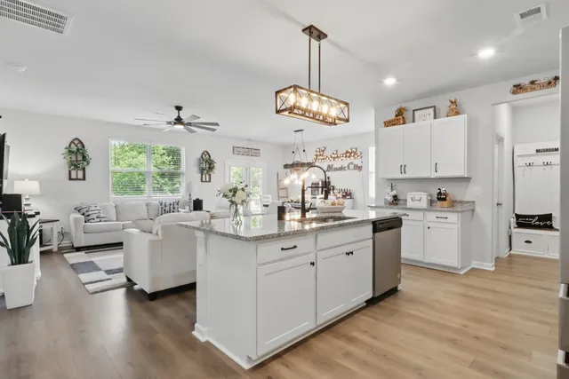 a large white kitchen with lots of counter space wooden floor and stainless steel appliances