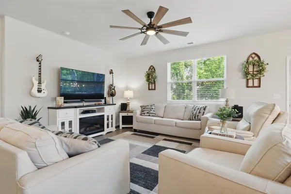 a living room with furniture a flat screen tv and a window
