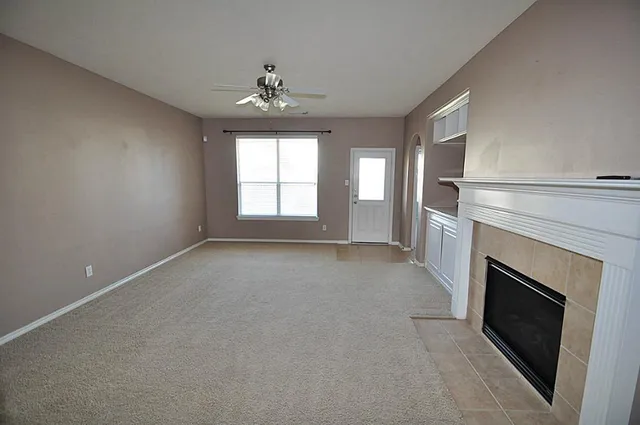 an empty room with windows and fireplace
