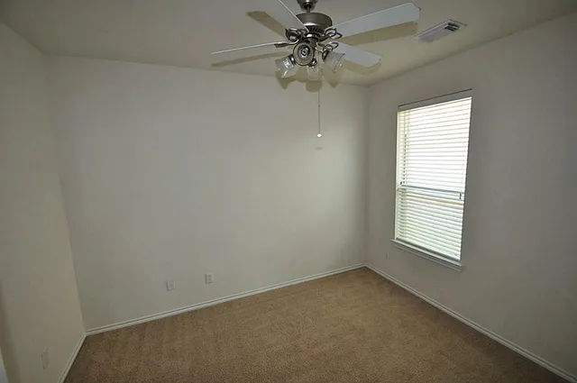 an empty room with windows and fan